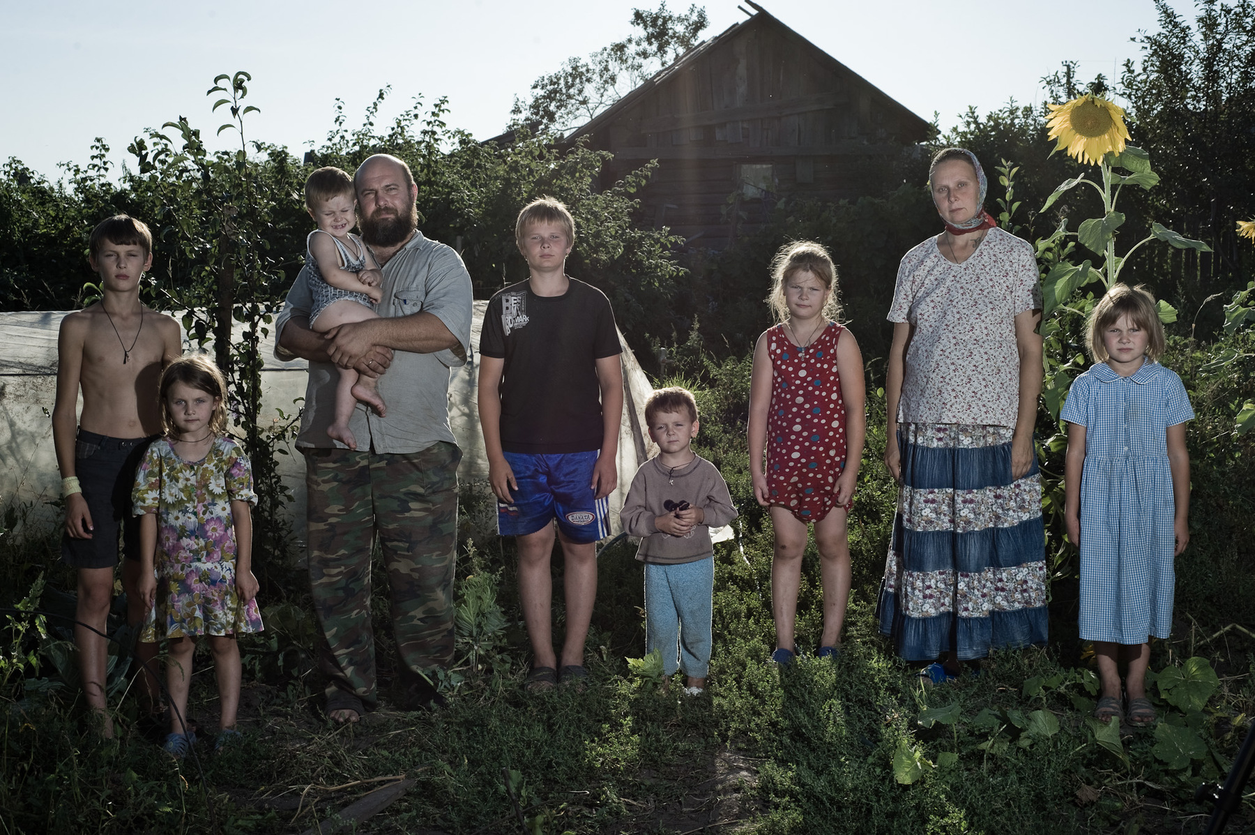 Konstantin Salomatin - Vyachkin family. From left to right: Korniliy, Elena, Andrey with his son Vitaly, Serafim, Andrey, Nastya, Natalia, Ekaterina. They have moved from Tashkent (Uzbekistan) in the middle of 90th. Andrey: There are a lot of weirdies here. They are scared of Tax ID, passports, the apocalypse, Antichrist.. But you have to be afraid of Christ and live according to your good conscience. God is with us. One has to believe.. Diveevo, Nizhny Novgorod region, Russia. 2011